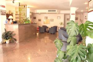 un vestíbulo con una sala de espera con sillas y plantas en Riccio Hotel, en La Maddalena
