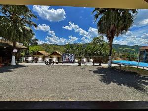 a park with benches and a pool and a palm tree at Pousada Pé da Serra in Lindóia