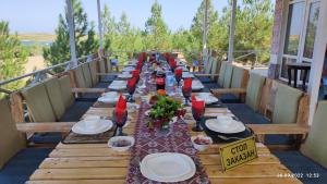 a long wooden table with plates and wine glasses on it at Nurata Ecotourism Guesthouse in Yukary-Ukhum