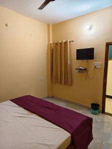 a bedroom with a bed and a tv on the wall at MAYUR paying Guest house in Varanasi