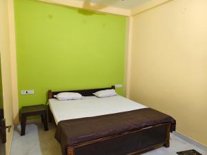 a bedroom with a bed with a green wall at MAYUR paying Guest house in Varanasi +13 photos