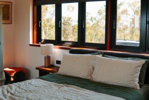 a bedroom with a bed with two windows at The Ridge Retreat on Litchfield in Rum Jungle Station
