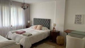 a bedroom with a bed with white sheets and pink pillows at Chalet Gasset in Mar del Plata +49 photos