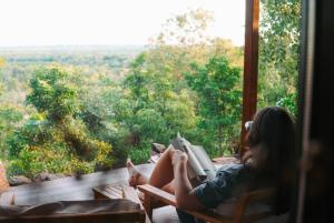 a woman sitting on a porch reading a book at The Ridge Retreat on Litchfield in Rum Jungle Station