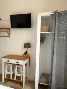 a room with a table and a tv on a wall at Hôtel L'Escale Au Soleil in Saint-Aygulf