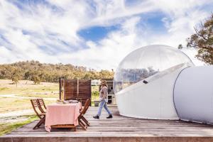 a man walking past a tent and a table at Captain Thunderbolt Bubbletent at Mirumiru in Tenterfield