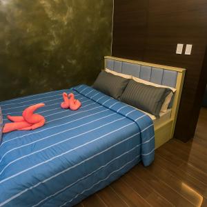 a bedroom with a blue bed with two pink pillows at The Comfy Cove Swim Stream in Central Makati 2272 in Manila