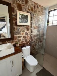 a stone bathroom with a toilet and a shower at Jacaranda Cottage, Rugando in Kigali +30 photos