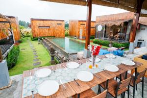 a wooden table with white plates on it next to a pool at Nila Chandra Bungalows in Ubud