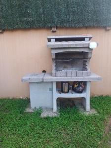 a stone oven sitting in the grass next to a building at Les Caramboles- Appartement Cosy in Sainte-Suzanne