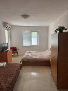 a bedroom with two beds and a chair and a window at Апартамент за гости ''ЗДРАВЕ'' in Kyustendil