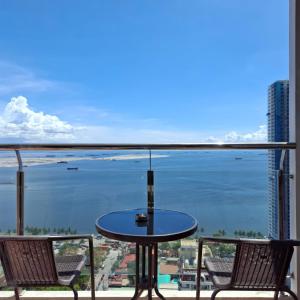 a table on a balcony with a view of the ocean at STAYLUXIA - MANILABAYVIEW - Luxury and Superior Suites with, Balcony -except Studios- Pool, Netflix & Gym- Housekeeping Available - in Manila