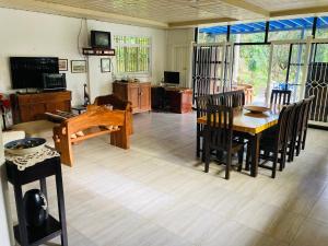 uma sala de estar com uma mesa e cadeiras de madeira em The poolhouse at McKirdy's mango farm em Sison