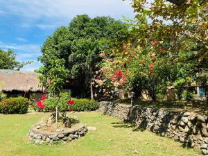 um jardim com flores e uma parede de pedra em The poolhouse at McKirdy's mango farm em Sison