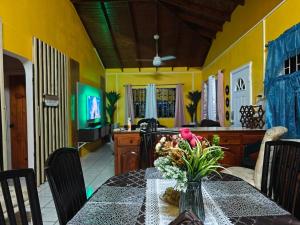 a dining room with a table with a vase of flowers on it at Risoli Villa in Micoud