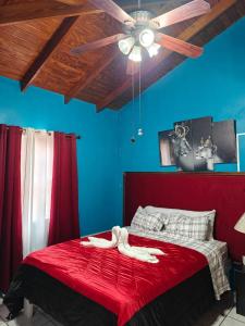 a bedroom with a red bed with a ceiling fan at Risoli Villa in Micoud +16 photos