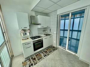 a kitchen with white appliances and a large window at Antonio's Home in Bari
