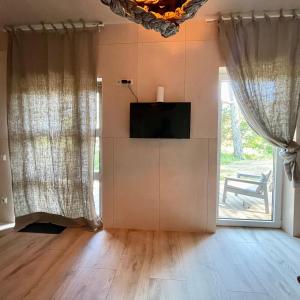 a living room with a tv and a large window at D a c h a in Ventspils