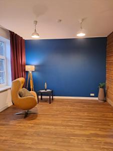 a living room with a chair and a blue wall at Hobupostijaama maja in Rapla