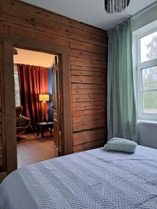 a bedroom with a large bed with a wooden wall at Hobupostijaama maja in Rapla