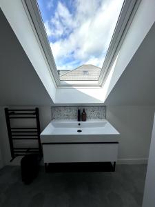 a bathroom with a skylight and a white sink at Kaimes Kip Stylish Edinburgh Five Bedroom Home in Edinburgh