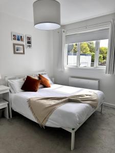 a bedroom with a white bed with pillows and a window at Kaimes Kip Stylish Edinburgh Five Bedroom Home in Edinburgh