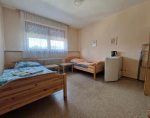 a bedroom with two beds and a refrigerator at Gasthaus für Monteure in Niederzissen +13 photos