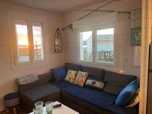 a living room with a couch and two windows at Le Chalet Beach Access 8 Pers in Gruissan