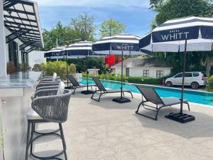 a group of chairs and umbrellas next to a pool at Hotel Whitt Hua Hin in Hua Hin