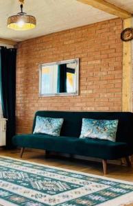 un divano verde in una stanza con muro di mattoni di Casa Craiului a Zărneşti