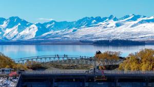 un puente sobre un cuerpo de agua con montañas cubiertas de nieve en Rivers Edge Studio, en Lake Tekapo