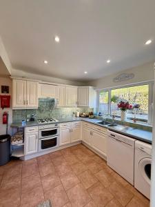 基斯利CANALSIDE Lovely location Walking distance to East Riddlesden Hall close to Worth Valley Railway , Haworth, Skipton, Ilkley & backs on to the Leeds-Liverpool Canal的厨房配有白色橱柜和大窗户