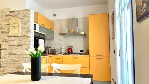 a kitchen with yellow cabinets and a table with a vase of flowers at Blueberry Villa - Historic Center in Luino