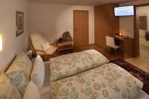 a bedroom with a bed and a chair and a table at Gästehaus Lässer in Mellau