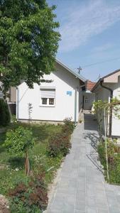 a white building with a tree next to a sidewalk at Apartman SLADJANA Vrnjacka Banja in Vrnjačka Banja