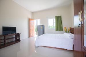 a white bedroom with a bed and a television at Praew Place Phimai in Ban Muang