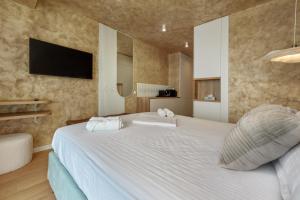 a bedroom with a large white bed with a tv on the wall at Studio South - VOGH in Olimp