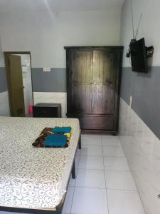 a bedroom with a bed and a wooden cabinet at Taman Paradise Homestay in Surabaya