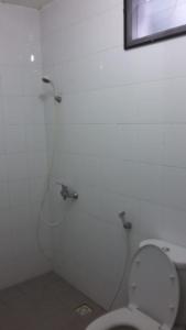 a white bathroom with a toilet and a shower at Taman Paradise Homestay in Surabaya