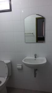 a white bathroom with a sink and a mirror at Taman Paradise Homestay in Surabaya