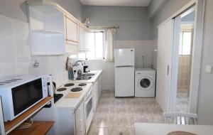 a white kitchen with a refrigerator and a sink at Casa alle terme in Loutra Edipsou