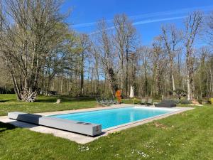 a person standing next to a swimming pool in a yard at La Chenaie - Les Accacias in Gien +4 photos