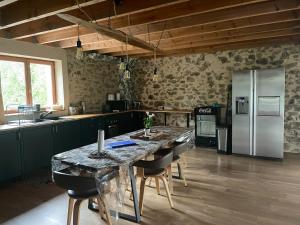 a kitchen with a table with chairs and a refrigerator at Grande maison conviviale in Neuvic-Entier