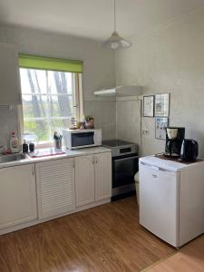 a kitchen with white cabinets and a sink and a microwave at Сottage under the trees in Rajaküla