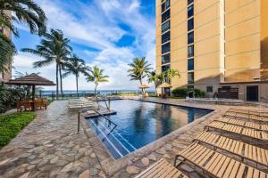 Una piscina en un resort con bancos y el océano. en Mahana 718, en Kahana
