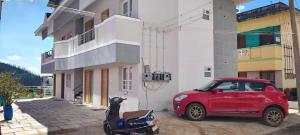 ウーティにあるLittle heavenのスクーターのある建物の隣に駐車された赤い車 +3枚の写真