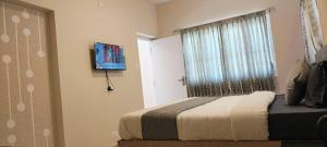 ウーティにあるLittle heavenの窓とテレビ付きのベッドのある寝室