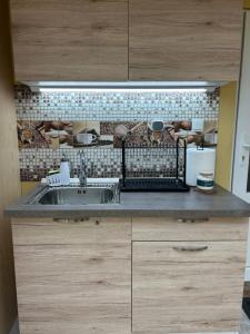 a kitchen with a sink and a tiled wall at Бунгала Мишел in Varna City