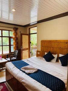 a bedroom with a large bed with a blue blanket at KEYAAN STAYS in Manāli