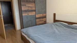 a bedroom with a bed and a wooden wall at Cozy apartment in Prishtinë